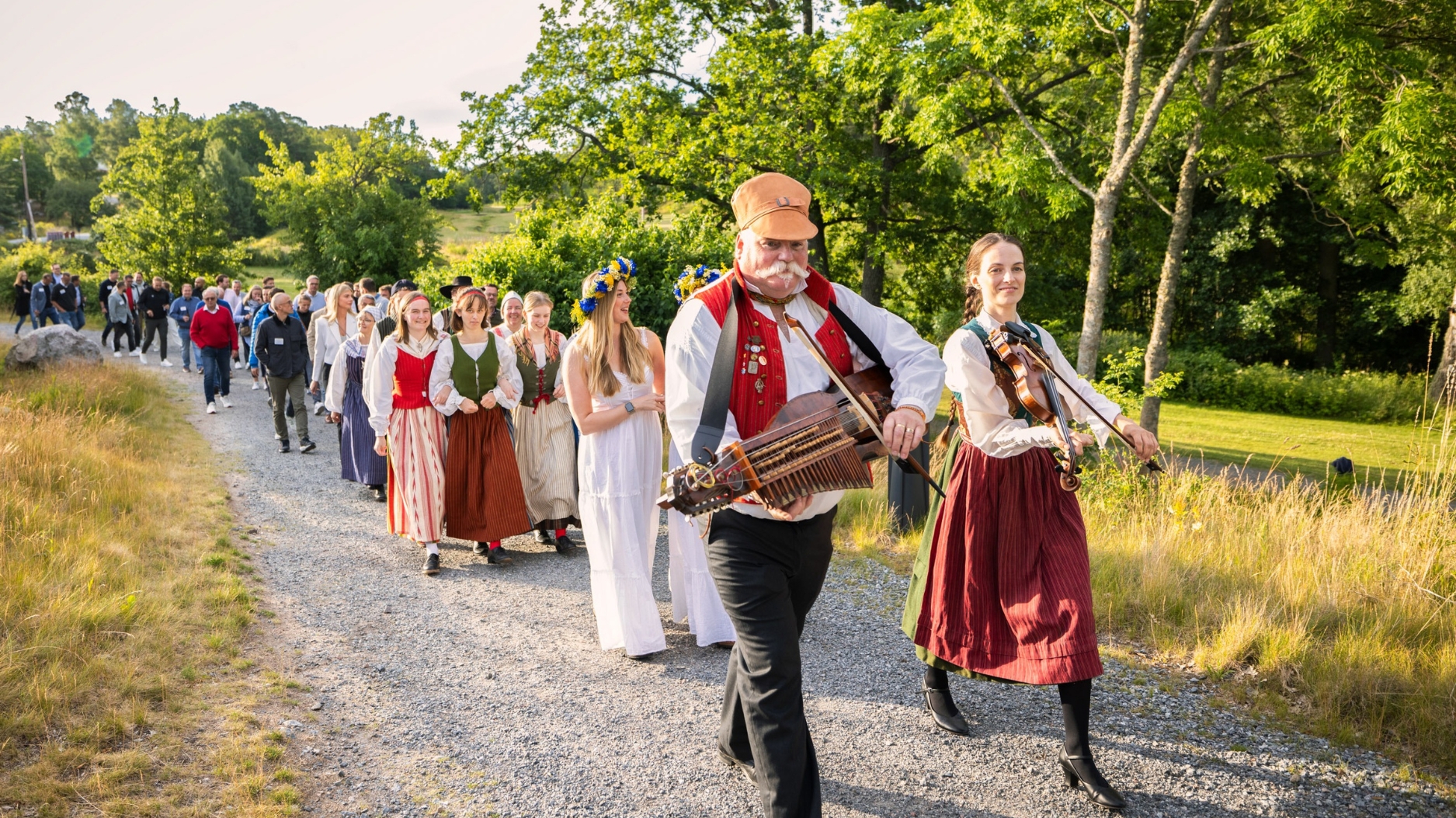 Folk musicians lead guests in traditional Swedish dress along the path