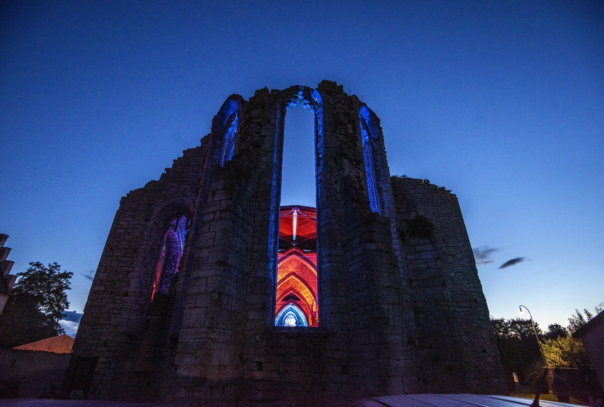 Visby church ruin lit in deep blue and red against the dusk sky