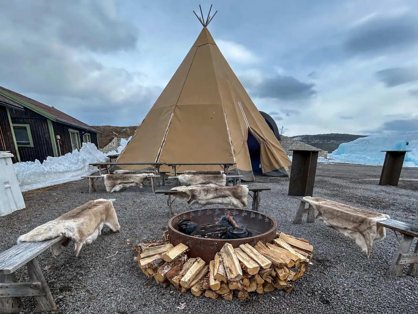 Sámi tipi and fire pit with reindeer hides at Icehotel