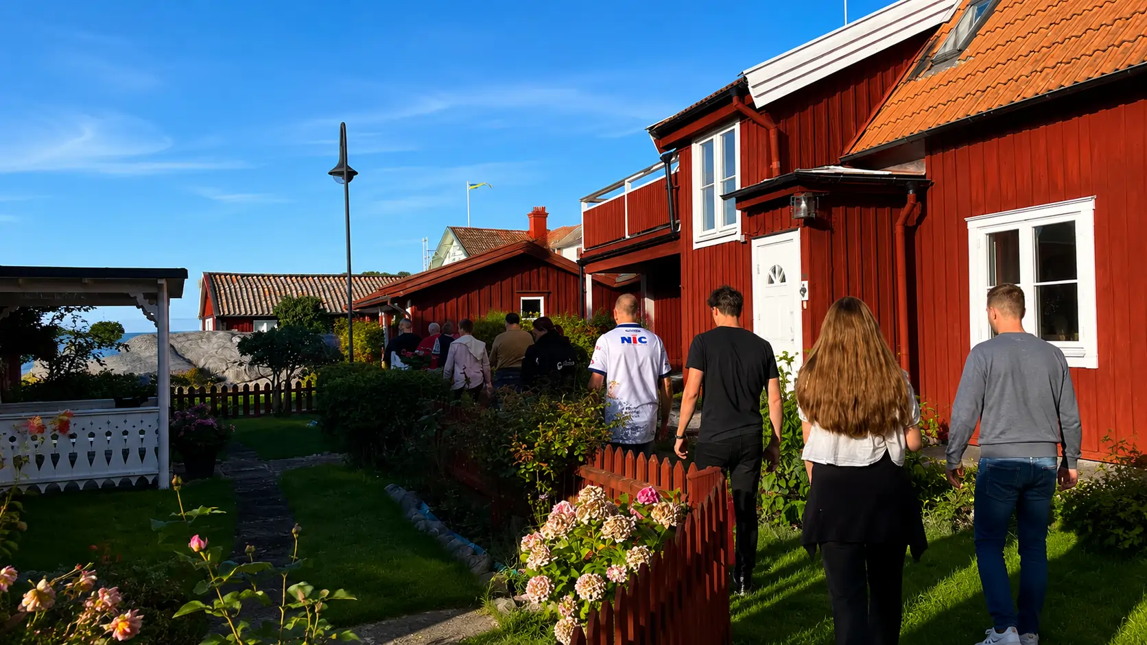 Group walking through the red wooden cottages of Sandhamn village